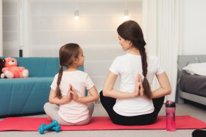 niña sana practicando yoga con su mama